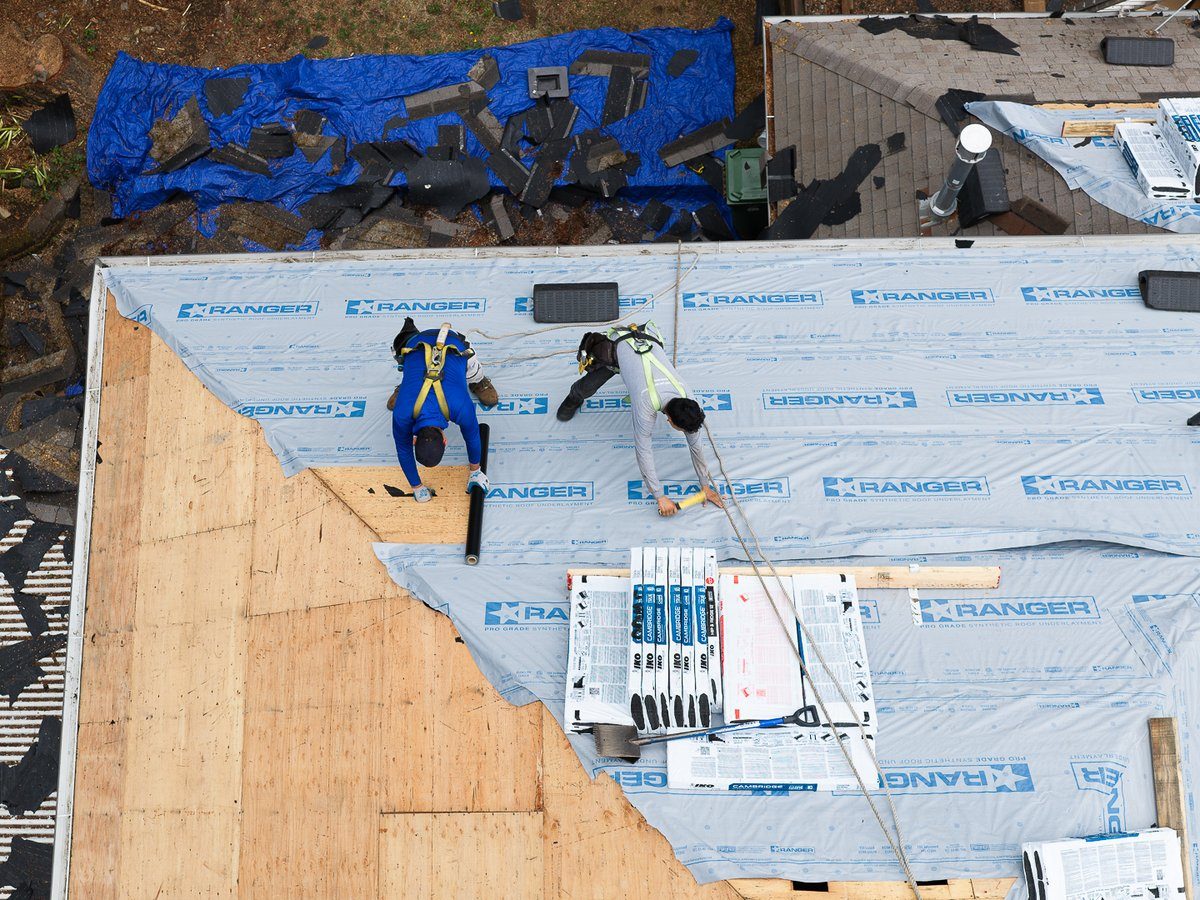 Overhead view of a Liberty roof tear-off with synthetic underlayment and shingle bundles staged